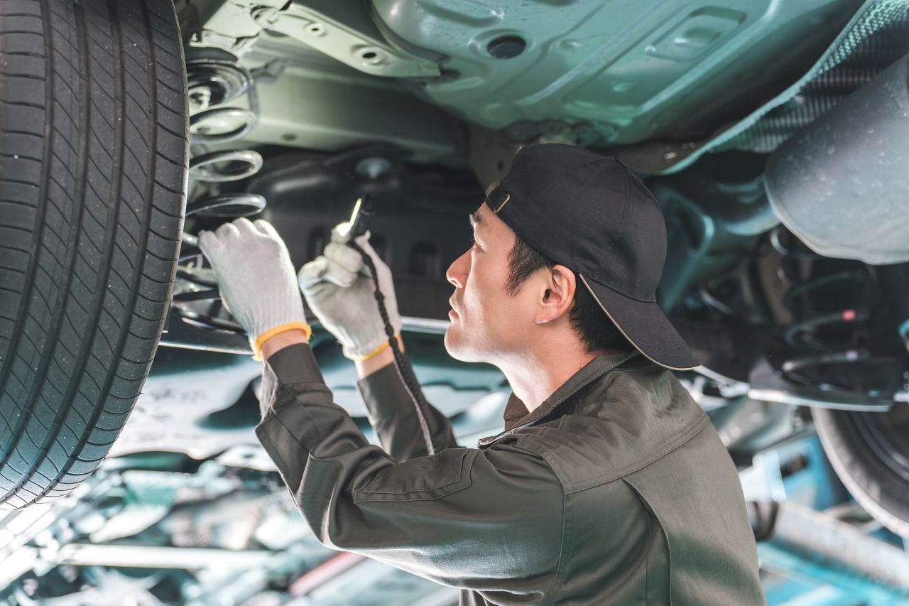 ライトを使って車の下回りを丁寧に点検している整備士