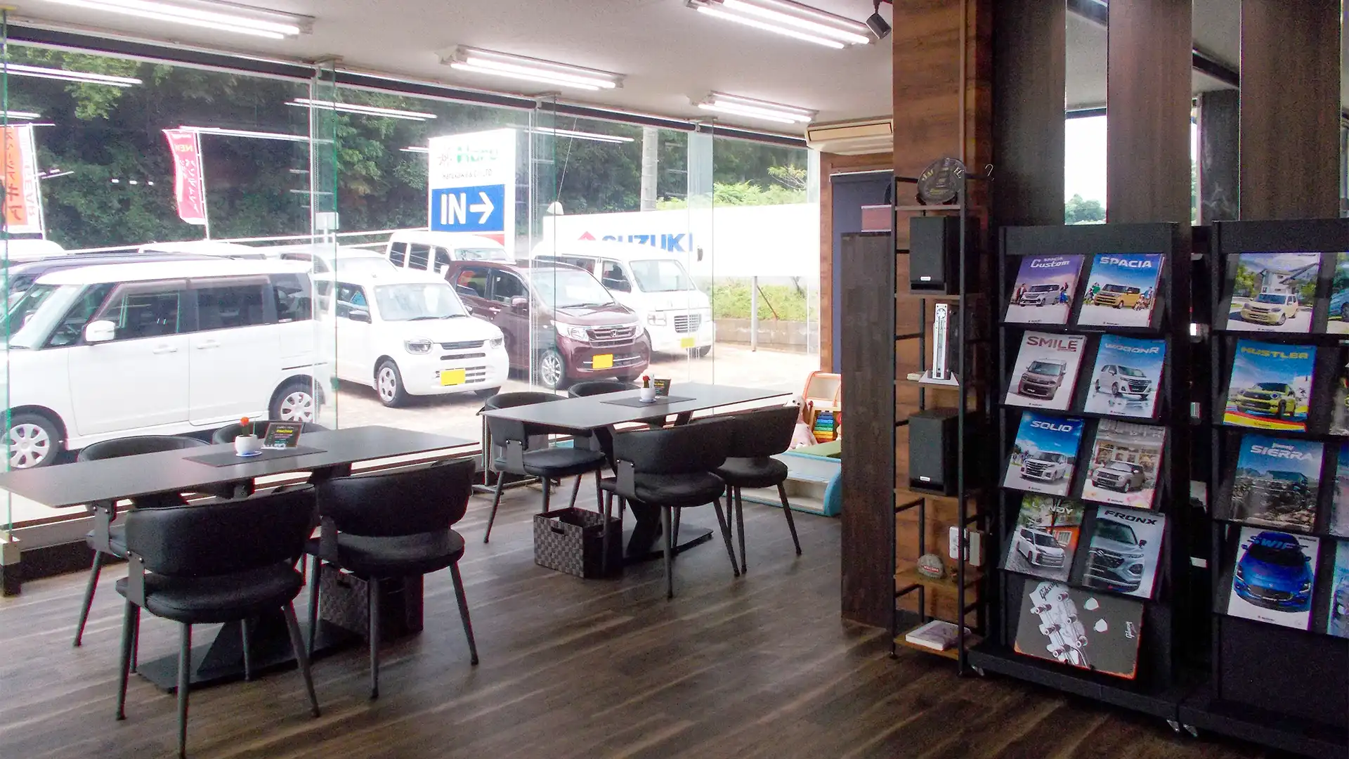 大きな窓に面した明るい商談スペース。窓の外には複数の展示車が並んでいる様子が見える