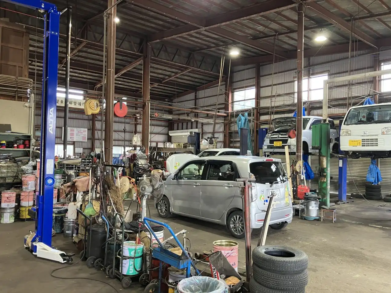 複数のカーリフトが設置され、車が整備されている整備工場内の様子